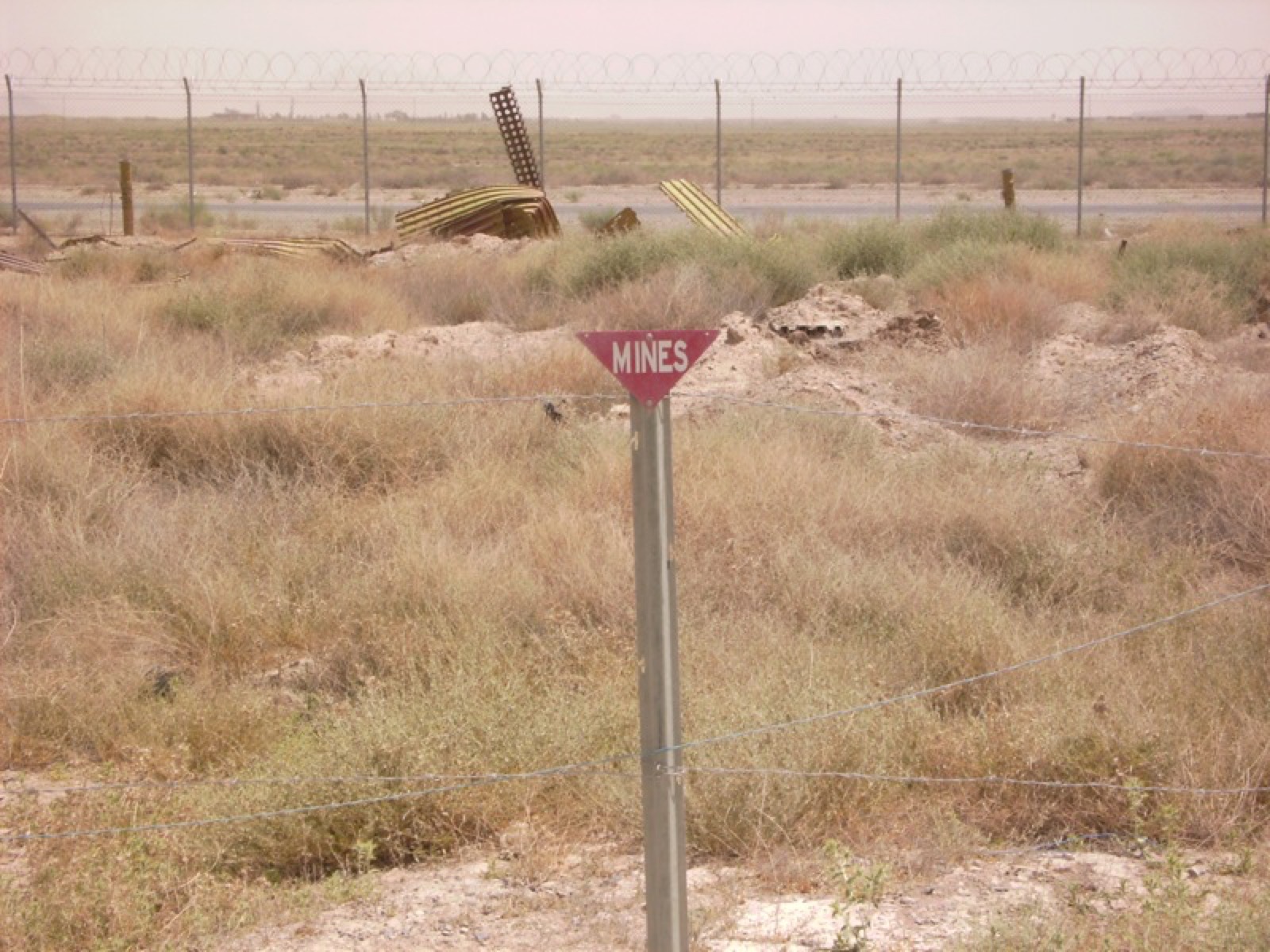 Beyond the wire, mined ground — marked